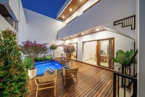 Zona de piscina exterior moderna amb terres de fusta, gandules i plantes en testos.