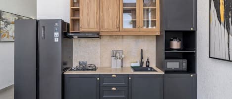 Una cocina moderna con estufa a gas integrada, microondas y refrigerador.