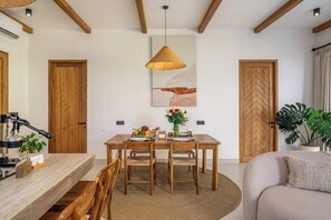 A dining area with a wooden table, chairs, a hanging light fixture, and a painting on the wall. - Serene 2BR Escape in Prime Ubud - Pool+Lush Jungle (Kabupaten Gianyar)