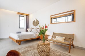Ein Schlafzimmer mit einem Bett, einem Nachttisch mit einer Vase, einer Korbschaukel und einem runden Beistelltisch.