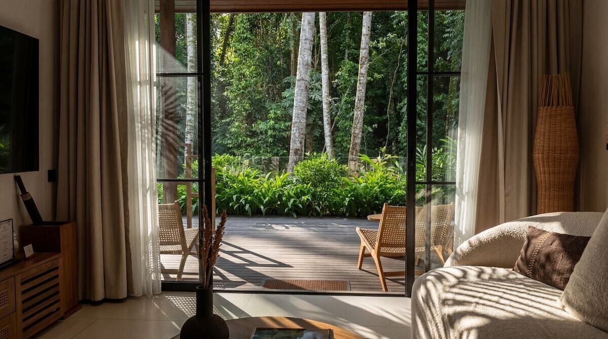 Une pièce avec une grande fenêtre, un canapé, un fauteuil et une table.