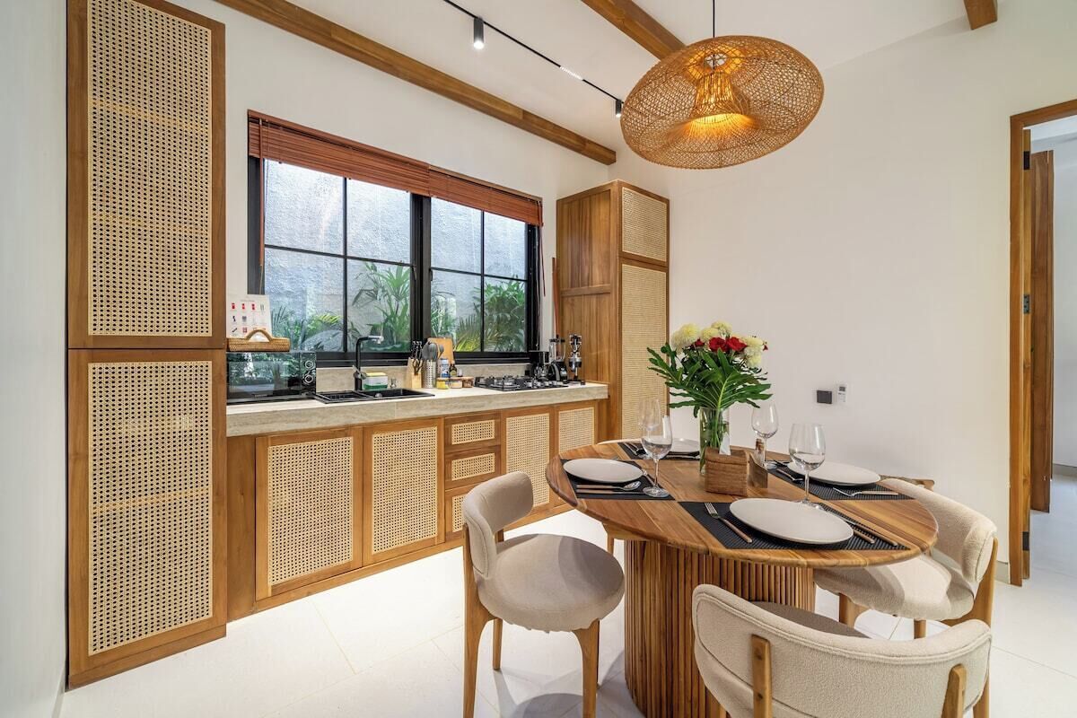 Une cuisine moderne avec un coin repas, dotée d’une grande fenêtre, de meubles en bois et d’une table à manger pour quatre personnes.