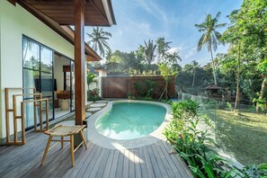 A swimming pool with a wooden deck, surrounded by tropical vegetation and palm trees. - Serene 2BR Stay in Top Ubud's Spot w Pool & Garden (Kabupaten Gianyar)