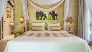 A large bed with a white bedspread, two pillows, and a headboard with a colorful abstract painting. - Peaceful Ubud's 1BR • Lush Garden • Pool • Patio (Gianyar Regency)