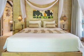 Ein großes Bett mit weißer Bettdecke, zwei Kissen und einem Kopfteil mit einem farbenfrohen abstrakten Gemälde.
