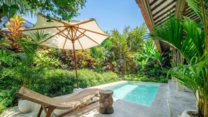 A pool area with a lounge chair, a small table, and a large umbrella. - Peaceful Ubud's 1BR • Lush Garden • Pool • Patio (Gianyar Regency)