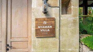 A wooden door and a stone wall with a sign that reads 'NYAMAN VILLA' by Evdeki. - Peaceful Ubud's 1BR • Lush Garden • Pool • Patio (Gianyar Regency)
