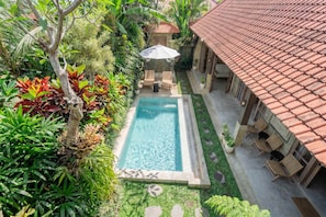 A swimming pool surrounded by lush greenery, with a tiled roof and outdoor seating area. - Serene Ubud 2BR Stay • Garden Bath • Private Pool (Ubud)