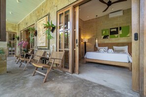 Une chambre d’hôtel avec un lit, un coin salon avec des fauteuils et une grande fenêtre.