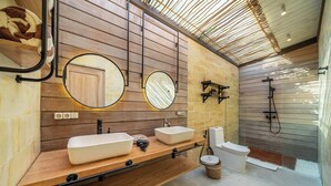 Een moderne badkamer met houten lambrisering, twee wastafels, een toilet en een douche.