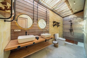 Ein modernes Badezimmer mit Holzwandverkleidung, zwei Waschbecken, einer Toilette und einer Dusche.