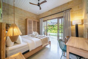 Ein Schlafzimmer mit einem Bett, einem Deckenventilator, einem Tisch und einem Stuhl.