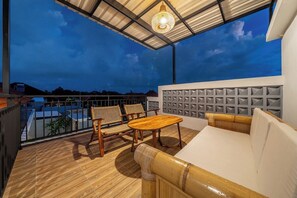 Ein Balkon mit Holzboden, einer Couch, zwei Stühlen und einem Tisch.