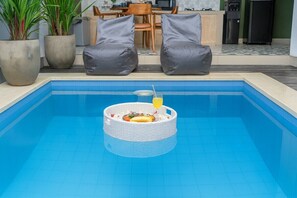 Una piscina con una cesta flotante que contiene comida y una bebida.