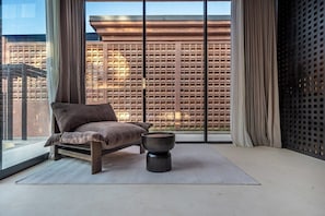 Ein moderner Raum mit großem Fenster, einer Couch, einem runden Tisch und einer Wand mit Muster.