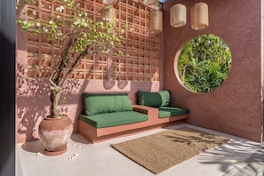 A modern outdoor seating area with a sofa, a large planter, and a circular window with greenery. - PROMO -20%OFF New 1BR Villa with Pool for Couples (Kabupaten Badung)