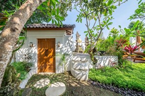 A traditional building with a wooden door, surrounded by lush greenery and stone structures. - Chic 1BR Stay w Garden Tub&Pool by Tropical Jungle (Kabupaten Gianyar)