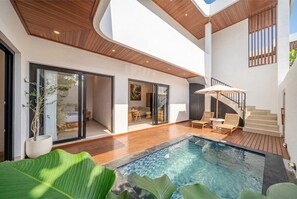 A modern interior with a swimming pool, wooden flooring, and a staircase leading to an upper level. - Designer 5BR in 500 m to Sanur Beach w Pool+Patio (Kota Denpasar)