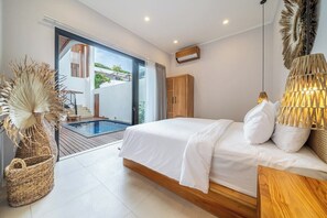A modern bedroom with a large bed, a wooden headboard, a bedside lamp, and a view of a swimming pool. - Designer 5BR in 500 m to Sanur Beach w Pool+Patio (Kota Denpasar)