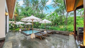A poolside area with lounge chairs and umbrellas, surrounded by lush greenery. - Boho 1BR Flat in Central Ubud w Pool, Garden&Patio (Kabupaten Gianyar)