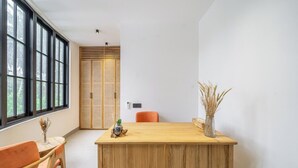 A room with a wooden reception desk, a chair, a window with blinds, and a door with a woven pattern. - Boho 1BR Flat in Central Ubud w Pool, Garden&Patio (Kabupaten Gianyar)