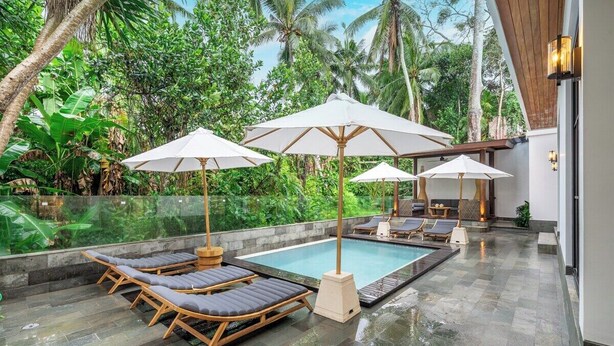 A pool area with lounge chairs and umbrellas, surrounded by lush greenery. - Boho 1BR Flat in Central Ubud w Pool, Garden&Patio (Kabupaten Gianyar)