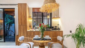A modern dining area with a round wooden table, four chairs, and a hanging light fixture. - Boho 1BR Flat in Central Ubud w Pool, Garden&Patio (Kabupaten Gianyar)