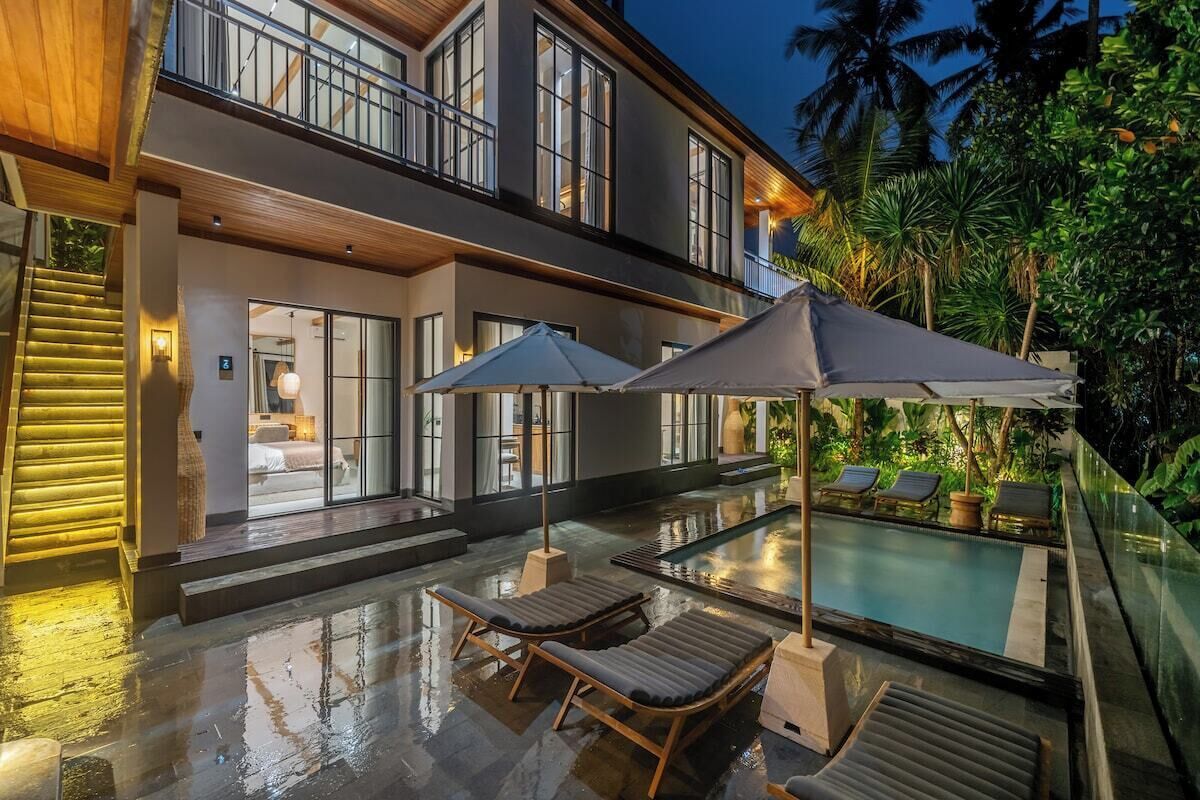 A modern house with a swimming pool, outdoor seating, and a staircase leading to the entrance.