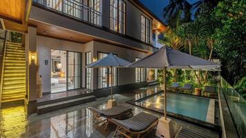 A modern house with a swimming pool, outdoor seating, and a staircase leading to the entrance.