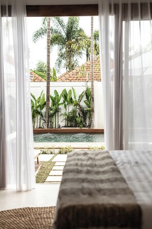 A bedroom with a view of a pool and tropical plants. - Peaceful 3BR Villa in Lush Ubud, Large Pool&Garden (Kabupaten Gianyar)