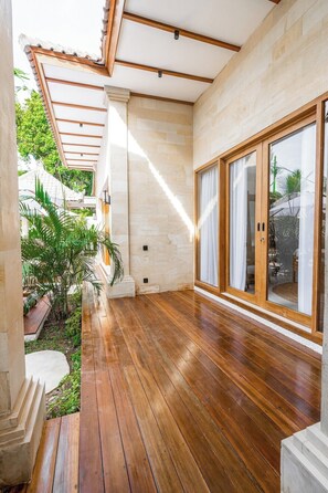 A wooden deck with a glass door leading to a covered patio area. - Peaceful 3BR Villa in Lush Ubud, Large Pool&Garden (Kabupaten Gianyar)