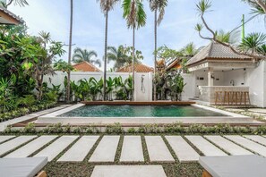 A swimming pool with a tiled deck, surrounded by palm trees and greenery, with a small bar area to the right. - Peaceful 3BR Villa in Lush Ubud, Large Pool&Garden (Kabupaten Gianyar)
