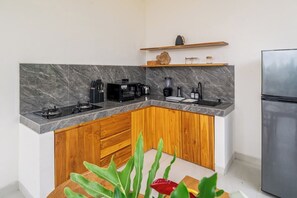 A modern kitchen with a marble countertop, wooden cabinets, and a built-in stove. - Chic 2BR Canggu Hideaway w Spacious Pool & Patio (Kabupaten Badung)