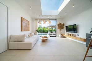 A modern living room with a sofa, coffee table, and a TV. - New 1BR Villa+Beach Access+Large Pool+South Kuta (Badung Regency)