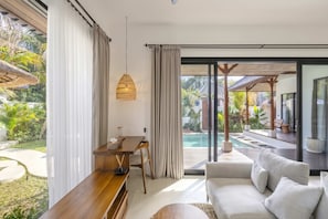 Ein modernes Wohnzimmer mit einer Couch, einem Esstisch und Blick auf einen Swimmingpool.