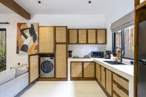 A compact kitchen with a washing machine, a microwave, and a sink. - New Chic 2BR Villa • Huge Pool • Garden Bath+Patio (Gianyar Regency)