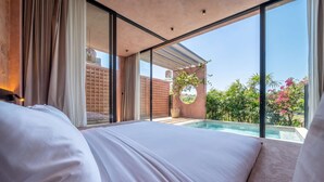 Un dormitorio con una cama grande, vista a una piscina y una pared de ladrillo.
