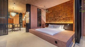 Un dormitorio moderno con una cama grande, un muro decorativo y una zona de estar con sillas.