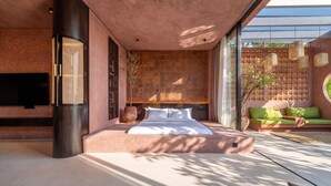 Un dormitorio moderno con una cama grande, un televisor y una zona de estar con un sofá verde.