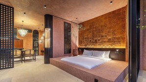 Ein modernes Schlafzimmer mit einem großen Bett, einer Wanddekoration und einer Sitzecke mit Sesseln.