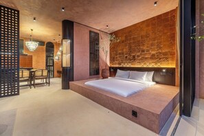 A modern bedroom with a large bed, a decorative wall, and a seating area with chairs. - Tropical 1BR Hideaway in Ungasan w Pool & Patio (South Kuta)