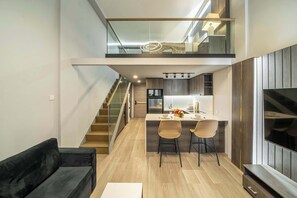 A modern kitchen with a dining area, a staircase, and a black sofa. - Aster Apartement 334 - 2-storey Flat w Beach Access, Pool, Gym & Sauna (Kabupaten Badung)