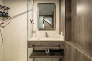Ein Badezimmer mit Spiegel, Waschbecken und Dusche.