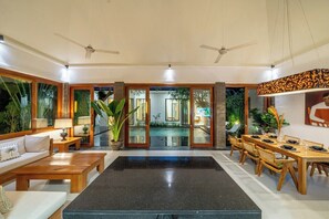 A spacious living area with a central black marble floor, wooden furniture, and a dining area with a long table and chairs. - Cozy 2BR near Canggu's Beaches w Pool & Garden (Kabupaten Badung)
