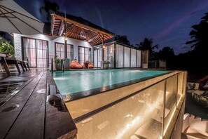 A swimming pool with a glass enclosure, wooden deck, and outdoor seating area. - Serene 2BR Ubud Oasis w Infinity Pool&Garden Bath (Ubud)