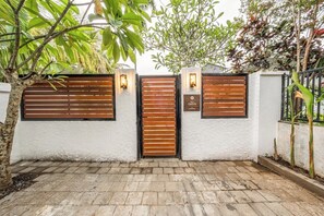 Een hekpoort met een houten poort en twee lantaarns aan de muur bevestigd.