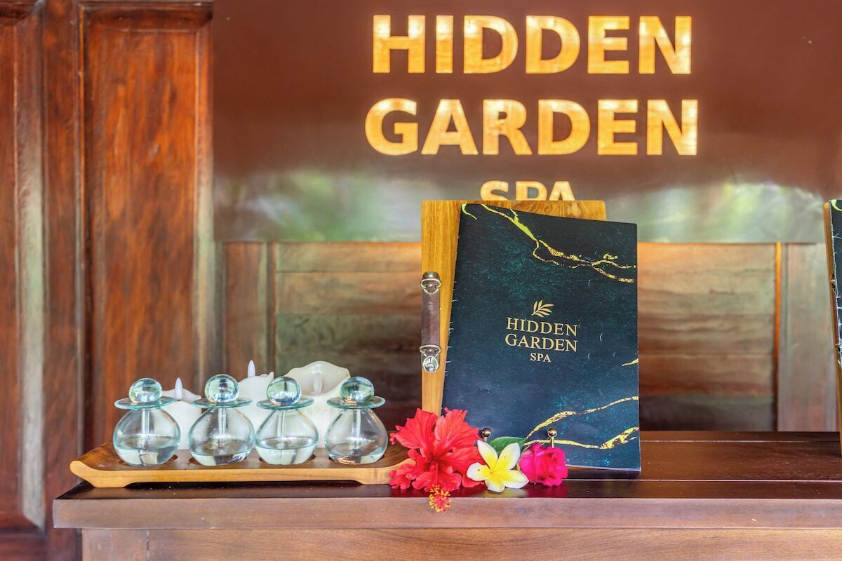 Un segnale per una spa con la scritta 'Hidden Garden Spa' e un espositore in legno con barattoli di vetro e fiori.