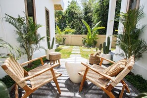 A patio with wicker furniture, a white ottoman, and potted plants. - Amazing Jungle view, 3BDR,  Canggu, huge Pool (Kabupaten Badung)