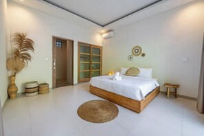 A bedroom with a wooden bed, a round woven rug, and a door leading to another room. - Amazing Jungle view, 3BDR,  Canggu, huge Pool (Kabupaten Badung)