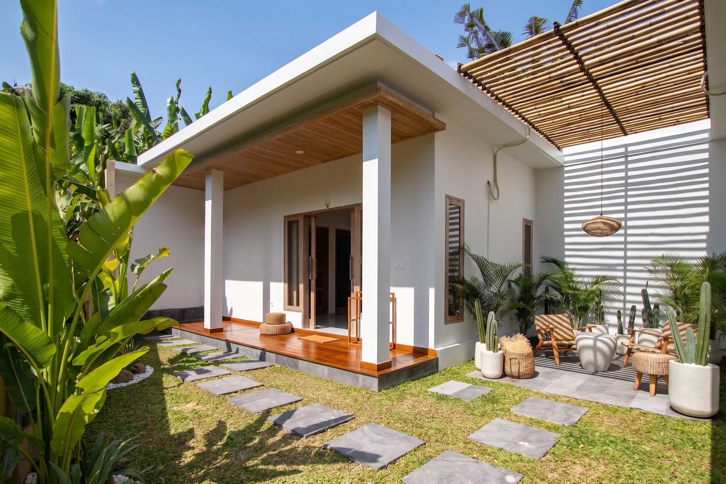 Una casa moderna amb un porxo cobert, un camí de pedra i plantes en testos.